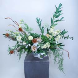 Large floral arrangement with white and peach blooms in a tall vase