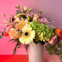 Mixed bouquet in a ribbed white vase with pink and green flowers