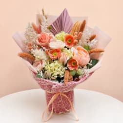 Peach and coral bouquet in pink wrap with ribbon