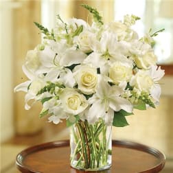 White lilies and roses arranged in a clear glass vase