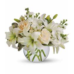 Low arrangement of white lilies and cream roses in a clear glass bowl vase