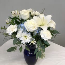 White roses, lilies, and daisies in a dark blue vase