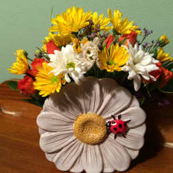 Mixed bouquet of yellow and white daisies with red roses in a decorative vase