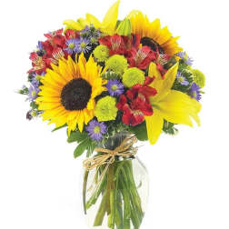 Bright mixed bouquet with sunflowers, lilies, and daisies in a glass vase