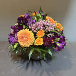 Mixed bouquet of orange, purple, and pink flowers in a glass vase