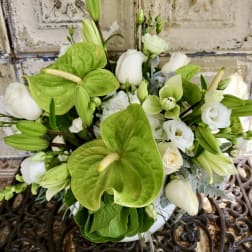 White and green floral arrangement with anthuriums, roses, and lilies in a vase
