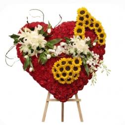Heart-shaped red floral arrangement with white lilies and yellow sunflowers on an easel