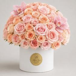Pink and peach roses arranged in a white hat box with two pink orchids