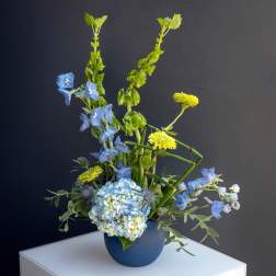 Blue and yellow floral arrangement in a blue vase