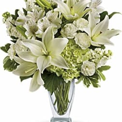 White lilies and mixed white flowers in a clear glass vase