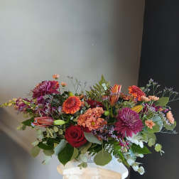 Mixed bouquet of roses, chrysanthemums, and lilies in a white vase