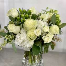 White roses and hydrangeas in a clear glass vase