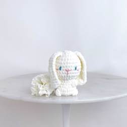White plush bunny figurine beside a white carnation on a round table