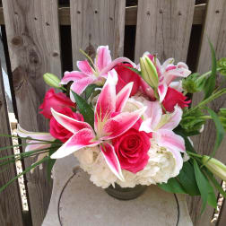 Pink lilies and roses arranged in a low vase