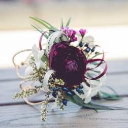 Small floral corsage with a dark purple bloom and white accents