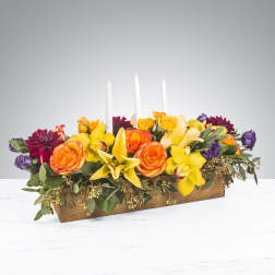 Low floral centerpiece with roses, orchids, and lilies in a wooden box with candles