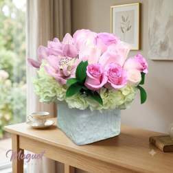 Pink roses and orchids arranged in a square vase