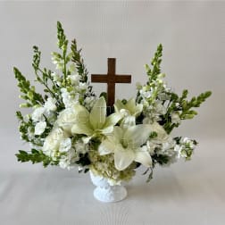 White floral arrangement with a wooden cross in a white vase