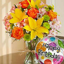 Bright mixed bouquet in a glass vase with a birthday balloon