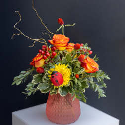 Orange roses and yellow flowers in a pink textured vase