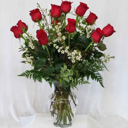 Red roses arranged in a clear glass vase with small white filler flowers.