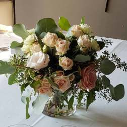 Blush and white roses in a clear glass vase with eucalyptus
