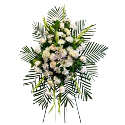 White funeral spray with roses, lilies, and daisies on palm fronds