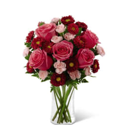 Pink roses and red daisies arranged in a clear glass vase