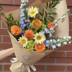 Bouquet of orange and pale yellow flowers wrapped in brown paper