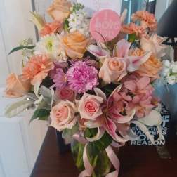Bouquet of peach and pink flowers in a glass vase with a pink "I Love You" pick