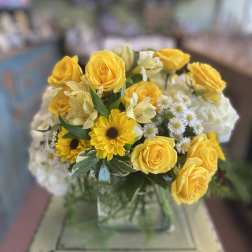 Yellow roses and daisies arranged in a glass vase