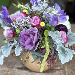 Mixed purple and pink bouquet in a tan vase