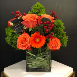 Orange roses and a gerbera daisy in a glass vase