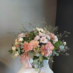 Pastel bouquet of roses, carnations, and small daisies with a pink ribbon