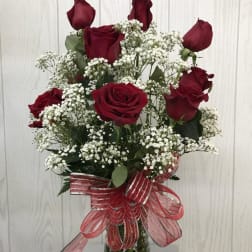 Bouquet of red roses and baby's breath in a glass vase with a red ribbon