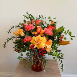Orange and pink floral arrangement in a red vase