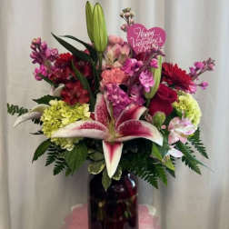 Mixed bouquet with lilies, roses, and pink flowers in a dark vase