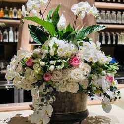Large white orchid and rose arrangement in a pedestal container