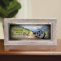Memorial plaque in a light wood frame with a motorcycle scene