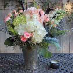 Mixed bouquet of pink, white, and green flowers in a metal vase