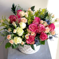 Pink and cream roses arranged in a white patterned bowl