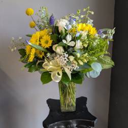Yellow and white mixed bouquet in a clear glass vase with a ribbon