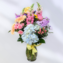 Colorful mixed bouquet in a glass vase with a yellow ribbon