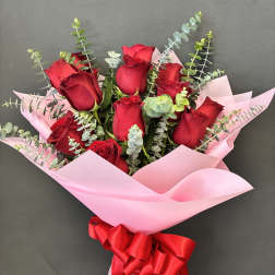 Bouquet of red roses wrapped in pink paper with a red ribbon