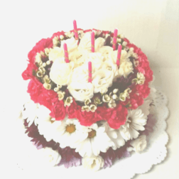 Round floral cake with white roses, daisies, and pink candles