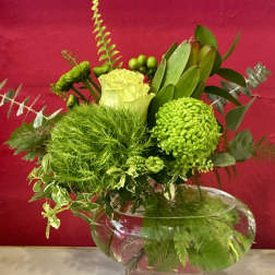 Green floral arrangement in a clear glass bowl vase