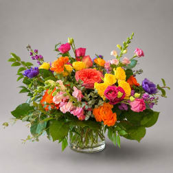 Colorful mixed bouquet in a clear glass vase with roses and snapdragons