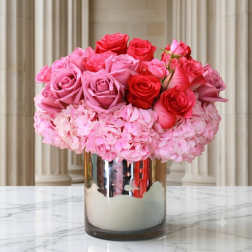 Pink and red roses arranged in a mirrored vase