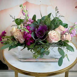 Pink and purple floral arrangement in a clear rectangular vase
