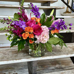 Mixed bouquet of pink, orange, and purple flowers in a glass vase